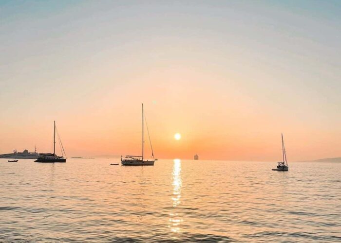 mykonos-sunset-greece-pilgrimage Mykonos sunset with sailboats greece pilgrimage tour