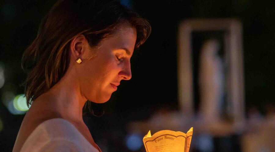 woman-candle-lourdes woman with candle at lourdes pilgrimage tour