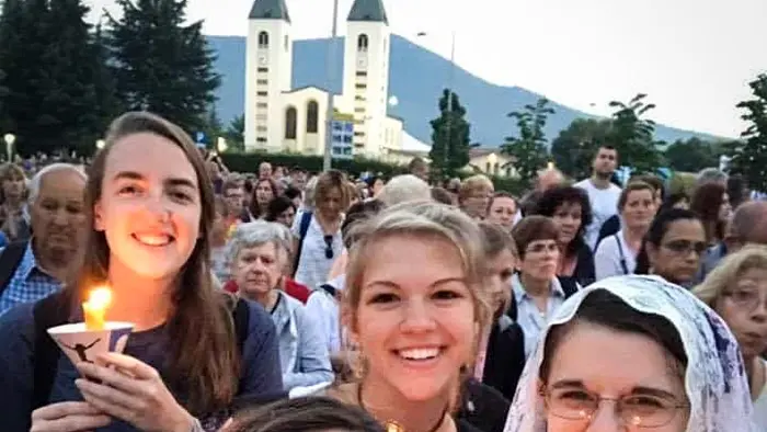 Smiling pilgrims in front of church in Medjugorje